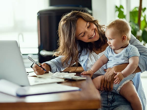 Young happy mother going through home finances and communicating with her baby son.