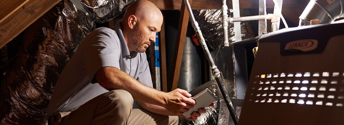 man servicing lennox heating unit in attic